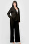 "Full-body shot of a model showcasing a sophisticated black blazer and trouser set with clear heeled sandals."