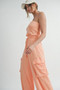 Full-length view of a peach strapless wide-leg jumpsuit featuring utility cargo pockets and a cinched drawstring waist in a textured, soft-touch fabric.