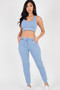 "A model posing in a coordinated two-piece set. The top is a fitted, sleeveless crop tank with a deep scoop neckline. The bottoms are relaxed-fit joggers featuring a ribbed drawstring waistband and cinched ankle cuffs."