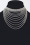 A sophisticated tiered bib necklace consisting of ten concentric rows of sparkling dark gemstones. The strands transition from a snug collar to a deep, elegant drape, creating a layered waterfall effect.