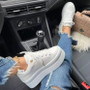 "Trendy street-style white platform sneakers paired with frayed hem jeans and a gold chain anklet."