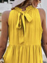 Tiered yellow shift dress with high neckline and ruffled hem, styled with a sun hat and accessories.