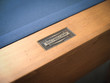 Doc & Holliday steel nameplate on end rail with glazed maple finish visible