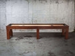 Studio view of Doc & Holliday Paula Parsons shuffleboard table showing full-length side profile in Natural Walnut