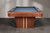 End view of the Doc & Holliday Preakness pool table highlighting the pedestal leg and vertical maple racing stripe detail against the walnut finish.