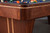 Close-up corner view of the Doc & Holliday Preakness pool table showing the maple racing stripe inlay against the walnut finish.