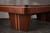 Ground-up view of the pedestal leg on the Doc & Holliday Preakness pool table, showing the walnut finish and maple racing stripe detail from the floor upward.