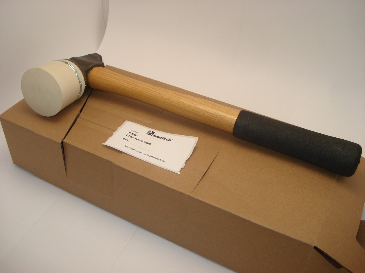 Primatech 2.8 lbs. 16" Mallet with a white cap and cast iron head lays on a cardboard box