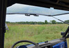 View from inside the cab of the SuperATV windshield flipped open with a grassy field beyond the Polaris Ranger hood