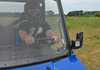 Front view through the closed SuperATV windshield of the helmeted driver in the blue Polaris Ranger, mirror with LED light