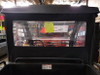 Rear view of the Side X Side cab enclosure rear window above the bed of a red utility side-by-side in a shop