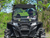 Front view of the black Polaris RZR with the SuperATV full windshield and roof installed on a wooded trail