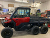 Red Can-Am Defender 6x6 with the Dirty Teeth Racing 2-inch lift installed, driver side front view in a shop
