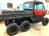 Passenger side profile of the red Can-Am Defender 6x6 with the Dirty Teeth Racing 2-inch lift kit in a shop