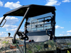 Spike rear windshield for Kawasaki Mule Pro-MX: rear windshield with vent seen through the cab of a camo UTV