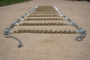 Eagle V-bar tire chain laid flat on pavement, showing the ladder-style cross links and end hooks