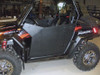 Side view of the black Trail Armor debris shield door panel installed on a black Polaris RZR inside a shop
