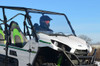 SuperATV scratch resistant full windshield on a white Kawasaki Teryx with a driver, front three-quarter view