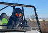 Close front view of a helmeted driver behind the SuperATV full windshield on the Kawasaki Teryx