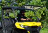 SuperATV scratch resistant flip up windshield raised on a yellow Can Am Defender, front three-quarter close view