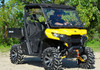 Full front three-quarter view of the yellow Can Am Defender with the SuperATV windshield down, mud tires and winch bumper