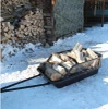 Moto Alliance Impact Implements snow sled with mesh side rails loaded with firewood on snow beside a woodpile