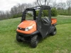 3 Star black full cab enclosure installed on an orange Kubota RTV in a field, front three-quarter view