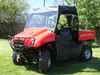 Black 3 Star full cab enclosure with vinyl windshield installed on a red Honda Big Red, front three-quarter view