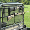 Great Day Power-Ride gun rack mounted on a UTV rear mesh screen holding a black rifle and a camo rifle