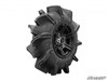 SuperATV Assassinator mud tire mounted on a black wheel, side view showing tall paddle-style tread lugs