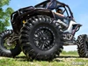 SuperATV Terminator mud tire close-up on the front of a black and white side-by-side with a beadlock wheel