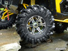 Close-up of a SuperATV XT Warrior tire on a yellow side-by-side climbing over rocks, showing the lugs