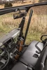 Kolpin vertical in-cab gun rack mounted between the seats of a UTV, holding a rifle below the roof bar