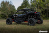 Front three-quarter view of the black Maverick X3 with SuperATV nerf bars, parked on grass with trees behind