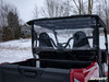 Close rear view of the SuperATV rear windshield behind the Yamaha Wolverine X2 seats with snowy trees behind