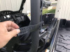 Hand holding the rubber mounting strap of the Extreme Metal Products cab back at the Yamaha Wolverine X2 cage bar