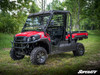 Red Kawasaki Mule FX with SuperATV cab enclosure doors installed, front three-quarter view on grass among trees