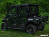 SuperATV four-door cab enclosure with clear doors installed on a black Kawasaki Mule FXT in a grass field, side view
