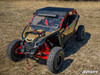 Tan and red Can-Am Maverick X3 fitted with the SuperATV aluminum roof, front three-quarter view in a field
