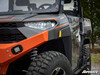 SuperATV recessed cube light flush mounted in the orange front bumper of a side-by-side, side angle by the headlight