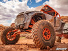 SuperATV XT Warrior SlikRok tires on orange beadlock wheels under a white side-by-side climbing red rock