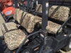 Greene Mountain camo seat covers installed on both rows of an orange Kubota RTV-X1140, side view through the cab
