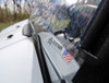 Close-up of the 3 Star one-piece windshield lower edge and clamp on the white hood of the Kawasaki Teryx 4
