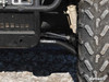 Close-up of the black SuperATV high clearance A-arm behind the front tire of a side-by-side on rocky ground