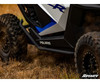 SuperATV nerf bar installed under the door of a white and blue Polaris RZR Pro XP parked in dry grass