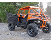 Rear three-quarter view of the orange Polaris RZR with the SuperATV aluminum driver door swung open