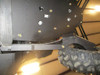 Trail Armor trailing arm guard installed under the rear of a Can-Am Maverick X3 in a shop, seen from below