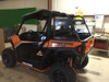 Side view of the orange Polaris General 1000 with the Trail Armor rear rack over the bed, parked in a shop