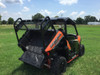Orange Polaris General 1000 in a grass field with the Trail Armor rear rack installed, rear three-quarter view