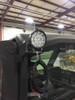 Round Universal Parts LED work light mounted on the rear cab corner of the Can-Am Defender with coiled wiring